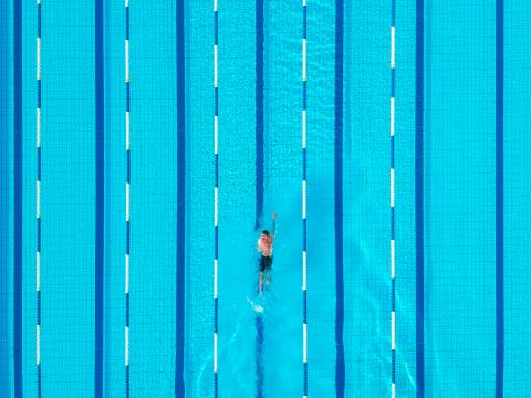 Schwimmer im Außenbecken des Schwimmerbeckens im Freibad der Bodensee-Therme beim Kraulen aus der Vogelperspektive auf der mittleren Bahn.