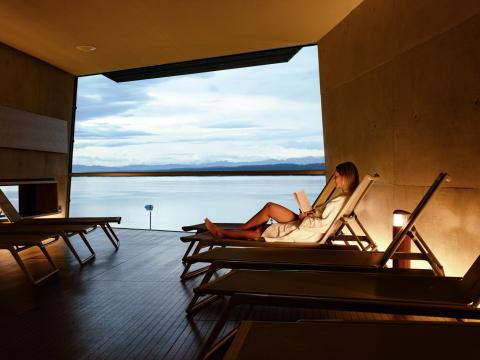 Frau im Relaxraum, entspannt, auf Liege, Blick über den See